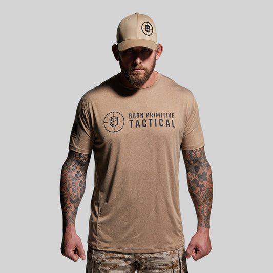 Man wearing a tan 'Born Primitive Tactical' t-shirt and cap on a gray background
