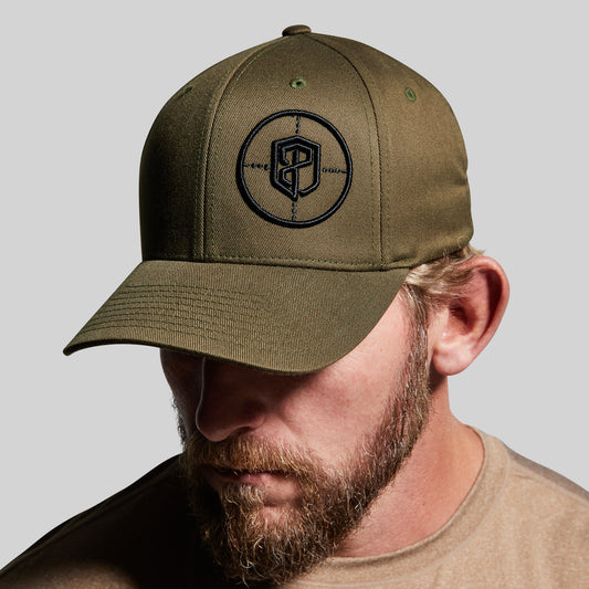 Man wearing a green cap with a logo on a gray background