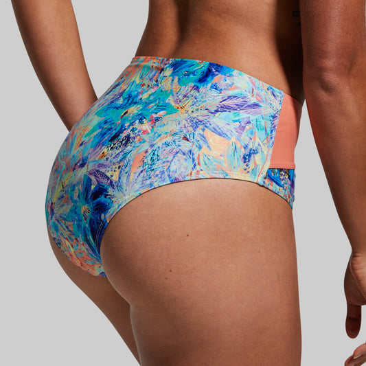 A rear view of a person wearing a multicolored floral bikini bottom with bright blue and flame design accents.