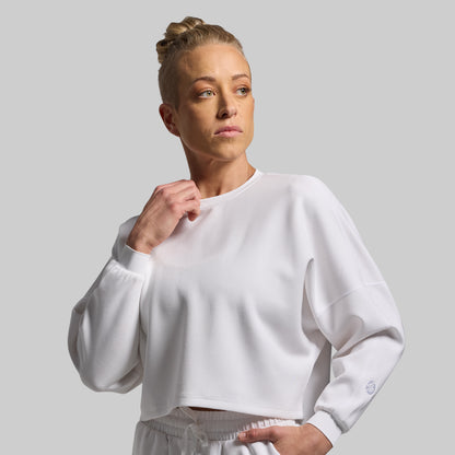 Person wearing a white sweatshirt against a plain background