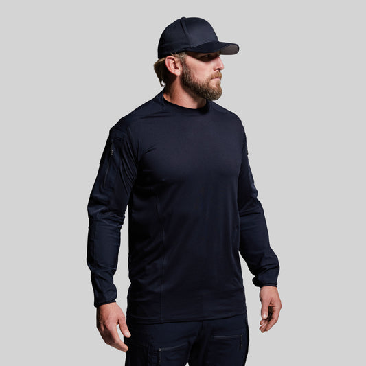 Man wearing a dark blue long-sleeve shirt and cap on a gray background