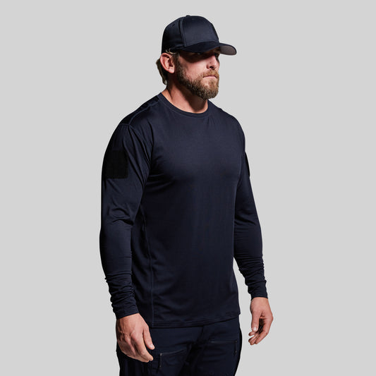 Man wearing a dark blue long-sleeve shirt and cap on a gray background