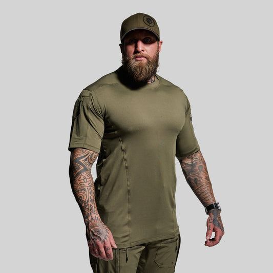 Man wearing an olive green t-shirt and cap on a gray background