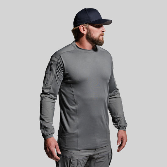 Man wearing a gray long-sleeve shirt and black cap on a light gray background