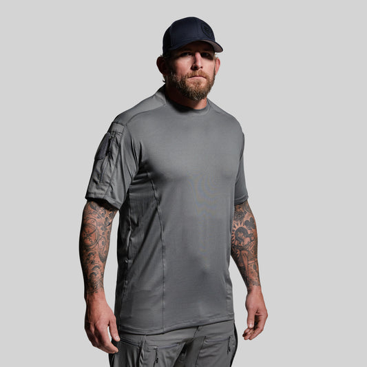 Man wearing a gray tactical outfit with a cap on a light gray background