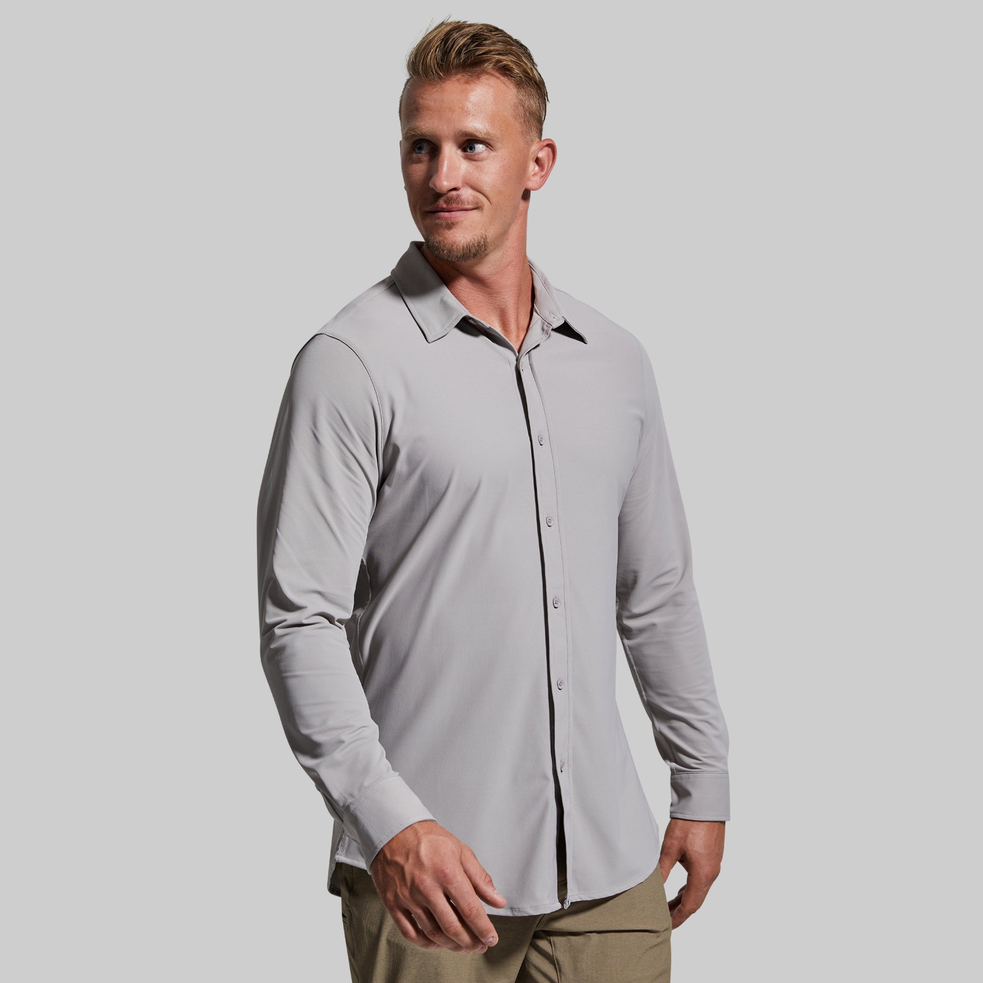 Man wearing a light gray button-up shirt with a plain background