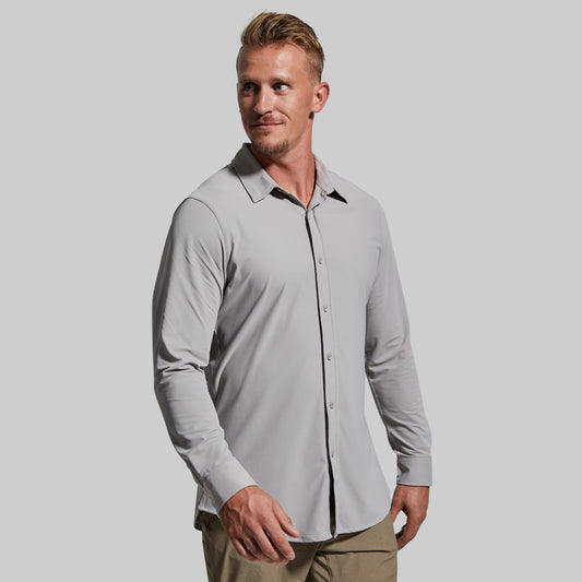 Man wearing a light gray button-up shirt with a plain background