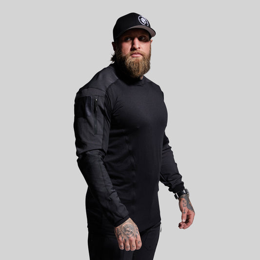 Man wearing a black long-sleeve shirt and cap on a gray background