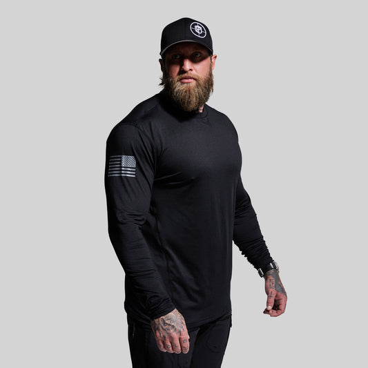Man wearing a black long-sleeve shirt and cap with a logo on a gray background