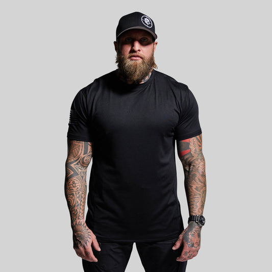Man wearing a black t-shirt and cap with tattoos on arms against a gray background