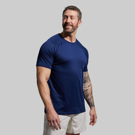 Man wearing a navy blue t-shirt and white shorts against a gray background