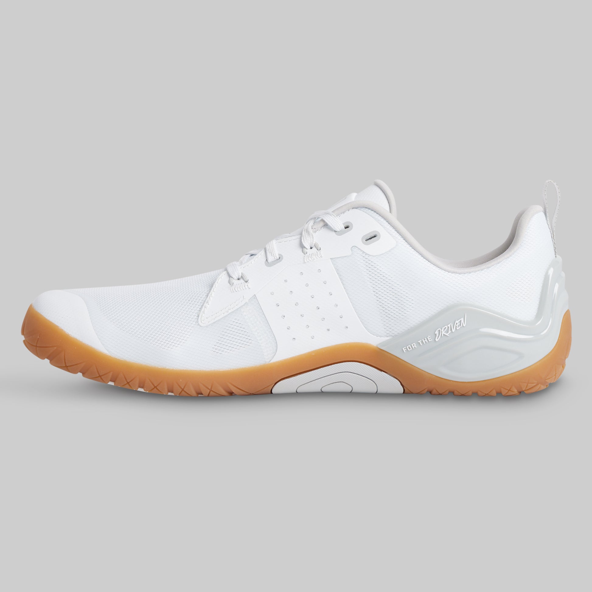 A white minimalist trainer shoe with a gum brown sole, shown in a side profile view against a solid gray background.