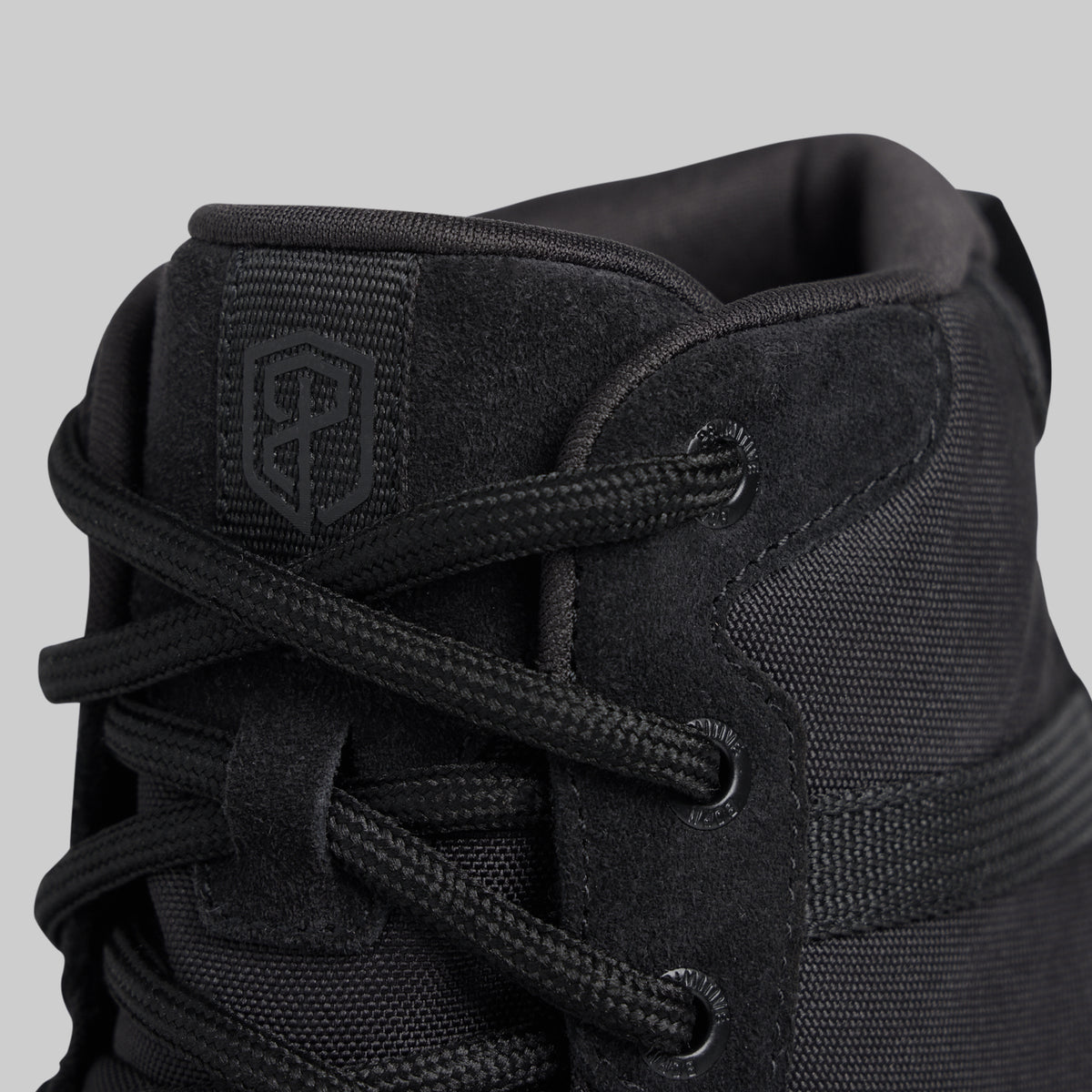 Close-up of a black high-top boot with brand logo on a gray background