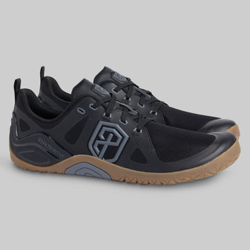 A pair of black athletic shoes with gray accents and a gum-colored sole, displayed on a neutral gray background.