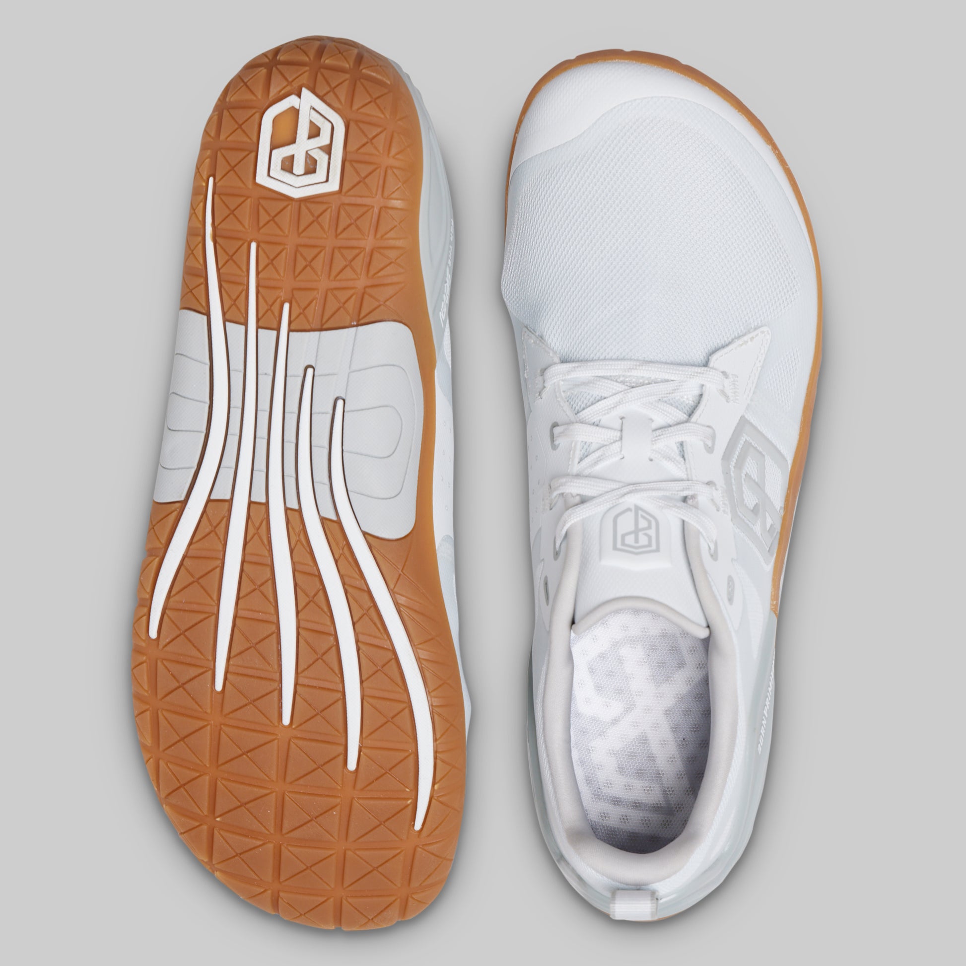 A pair of white athletic shoes shown from the top, displaying both the outsole and the top profile against a solid gray background.