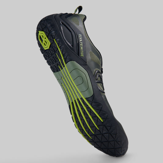 A single athletes barefoot shoe shown at an angle against a solid gray background, featuring a black and dark gray upper with olive green accents and bright neon yellow-green details on the sole.