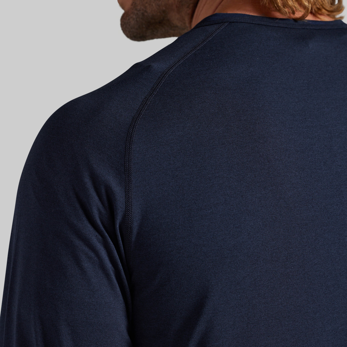 Close-up back view of a man wearing a dark navy long-sleeve athletic shirt, showing the shoulder seam and neck collar against a light gray background.