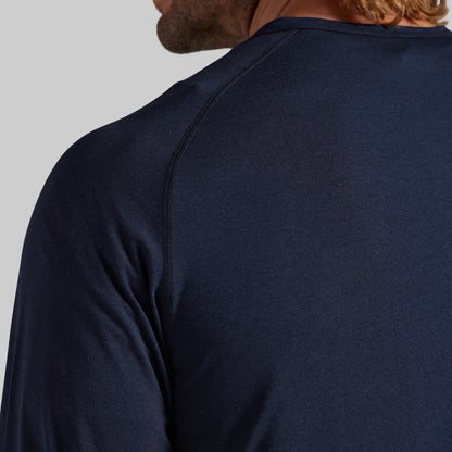 Close-up back view of a man wearing a dark navy long-sleeve athletic shirt, showing the shoulder seam and neck collar against a light gray background.