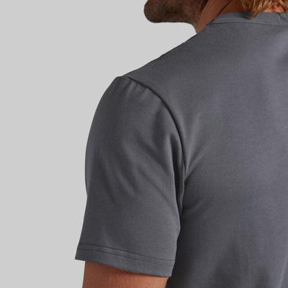 Close-up back view of a man wearing a dark gray crew-neck t-shirt against a light gray background.