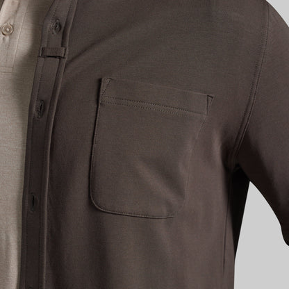 Close-up of a dark olive brown overshirt worn over a light beige polo shirt, highlighting chest pocket