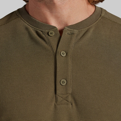 Close-up of a man wearing an olive green waffle-knit henley shirt with a three-button placket.