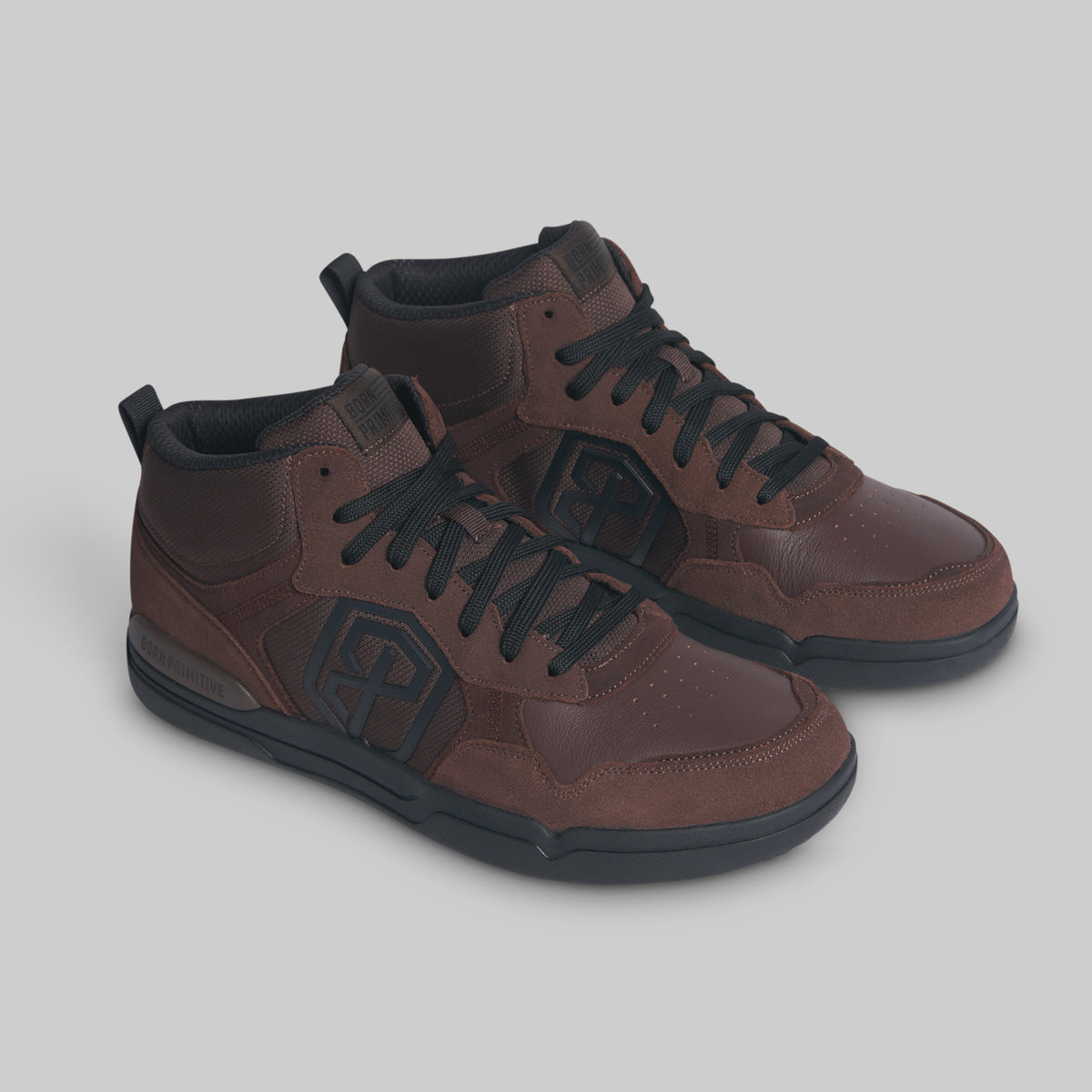 A pair of mid-top athletic sneakers in dark brown with black laces, black soles, and a tonal geometric logo on the side, displayed on a neutral gray background.