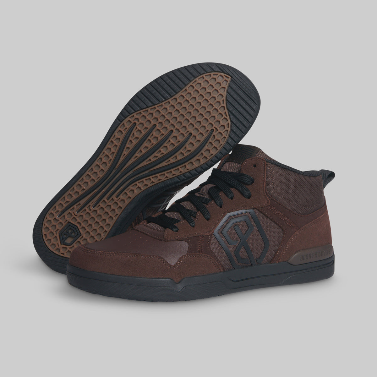 A pair of mid-top brown leather sneakers shown on a light gray background, with one shoe standing upright and the other lying on its side to display the textured brown outsole.