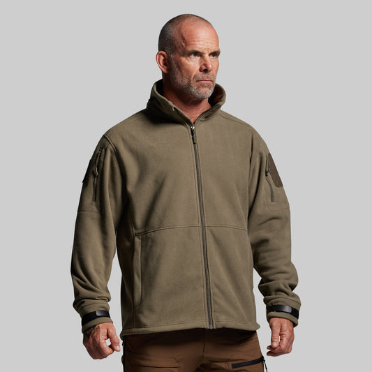 Man wearing a green tactical jacket on a gray background