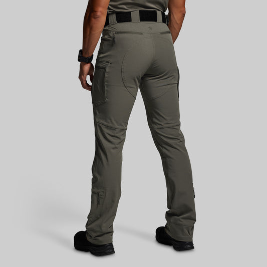 Person wearing olive green tactical pants on a gray background