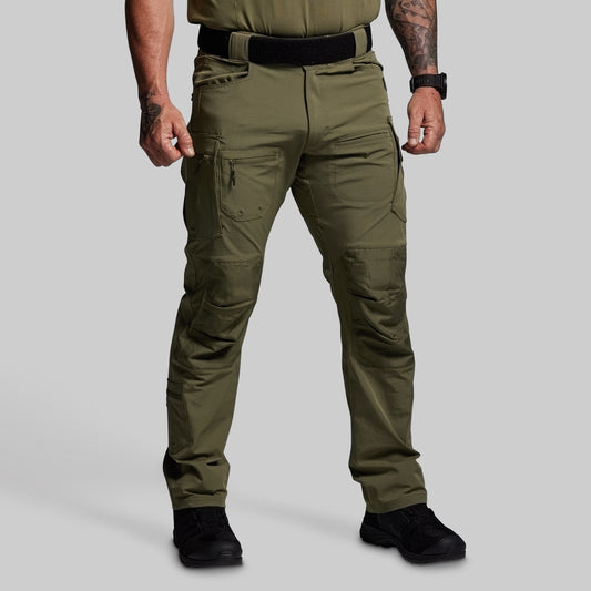Person wearing olive green tactical pants on a gray background