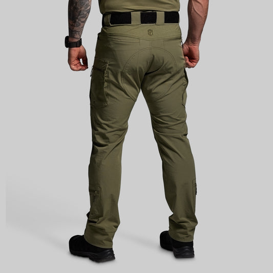 Person wearing olive green tactical pants on a gray background