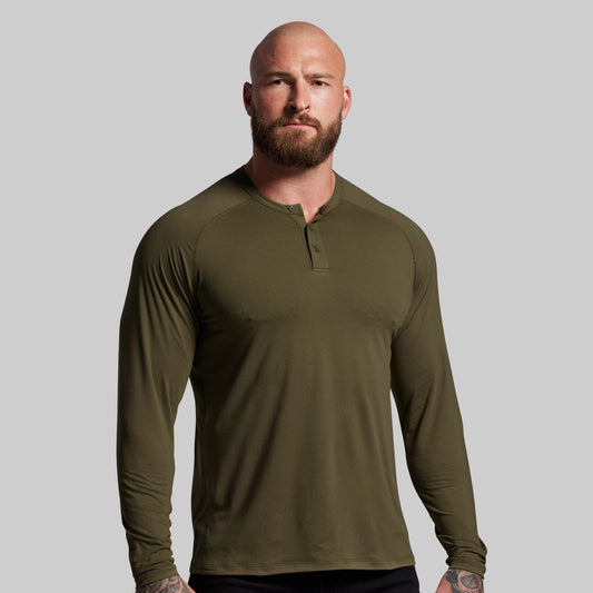 Man wearing an olive green long-sleeve shirt against a gray background