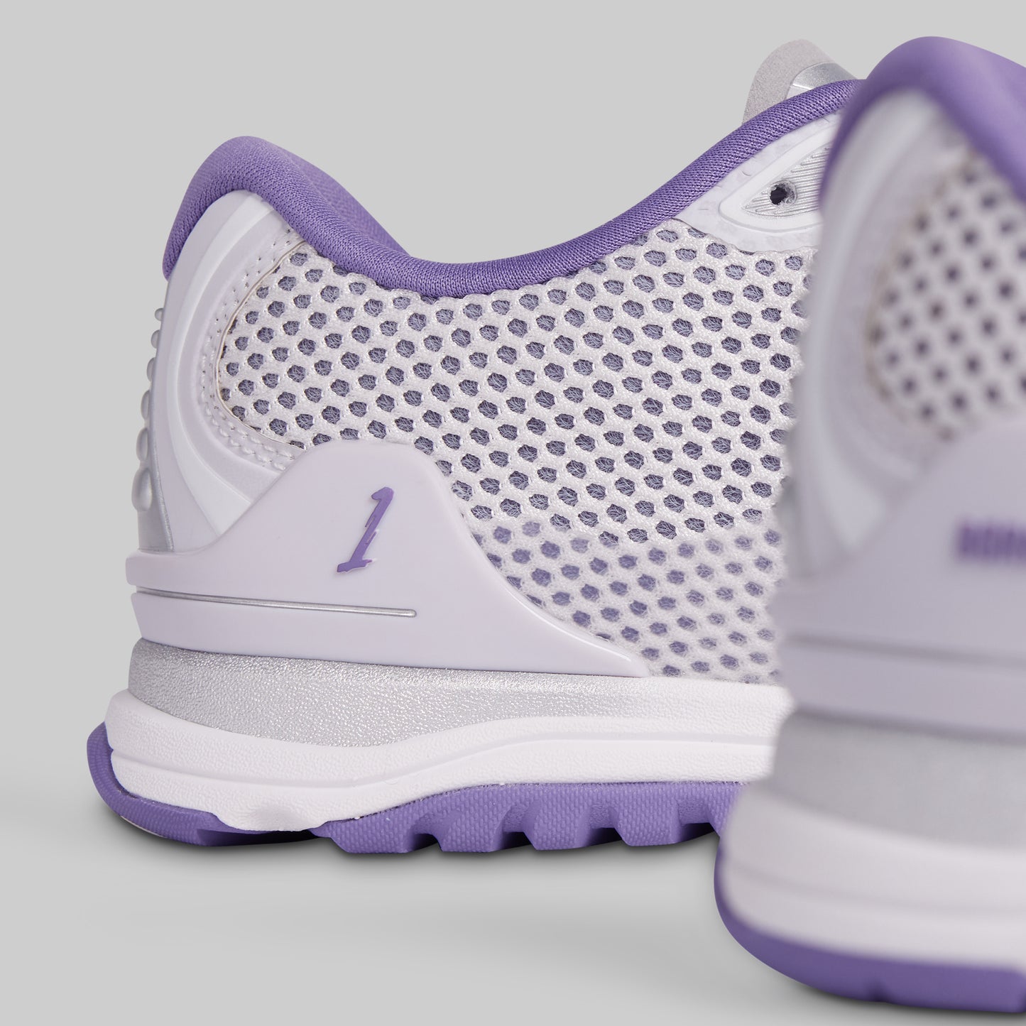 White and purple athletic shoe with mesh design on a light gray background