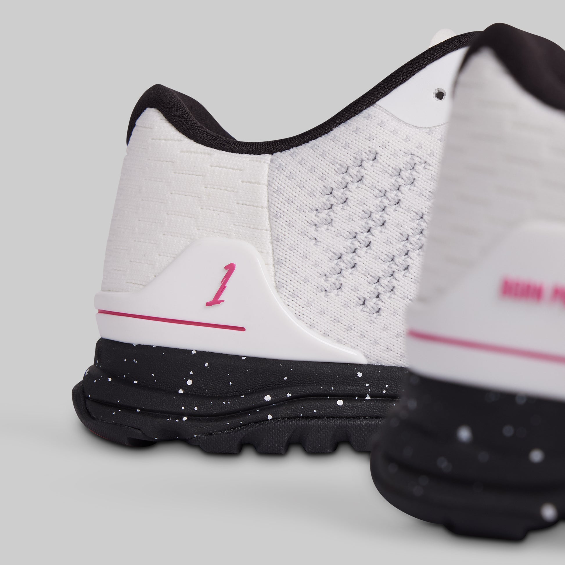White athletic shoes with black soles and pink accents on a light gray background