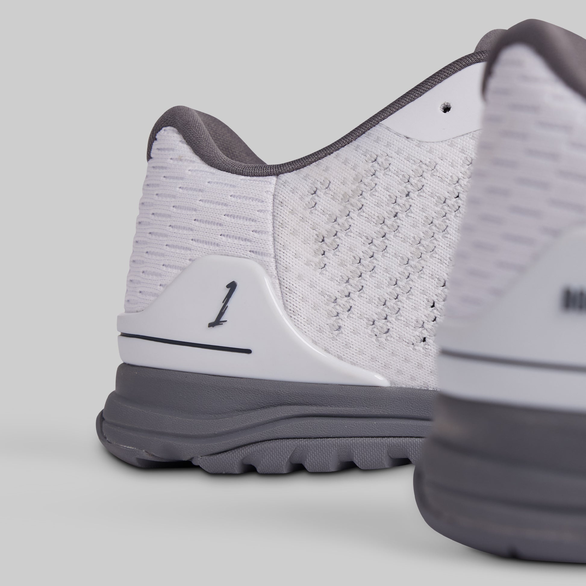 Close-up of a white and gray athletic shoe on a light gray background