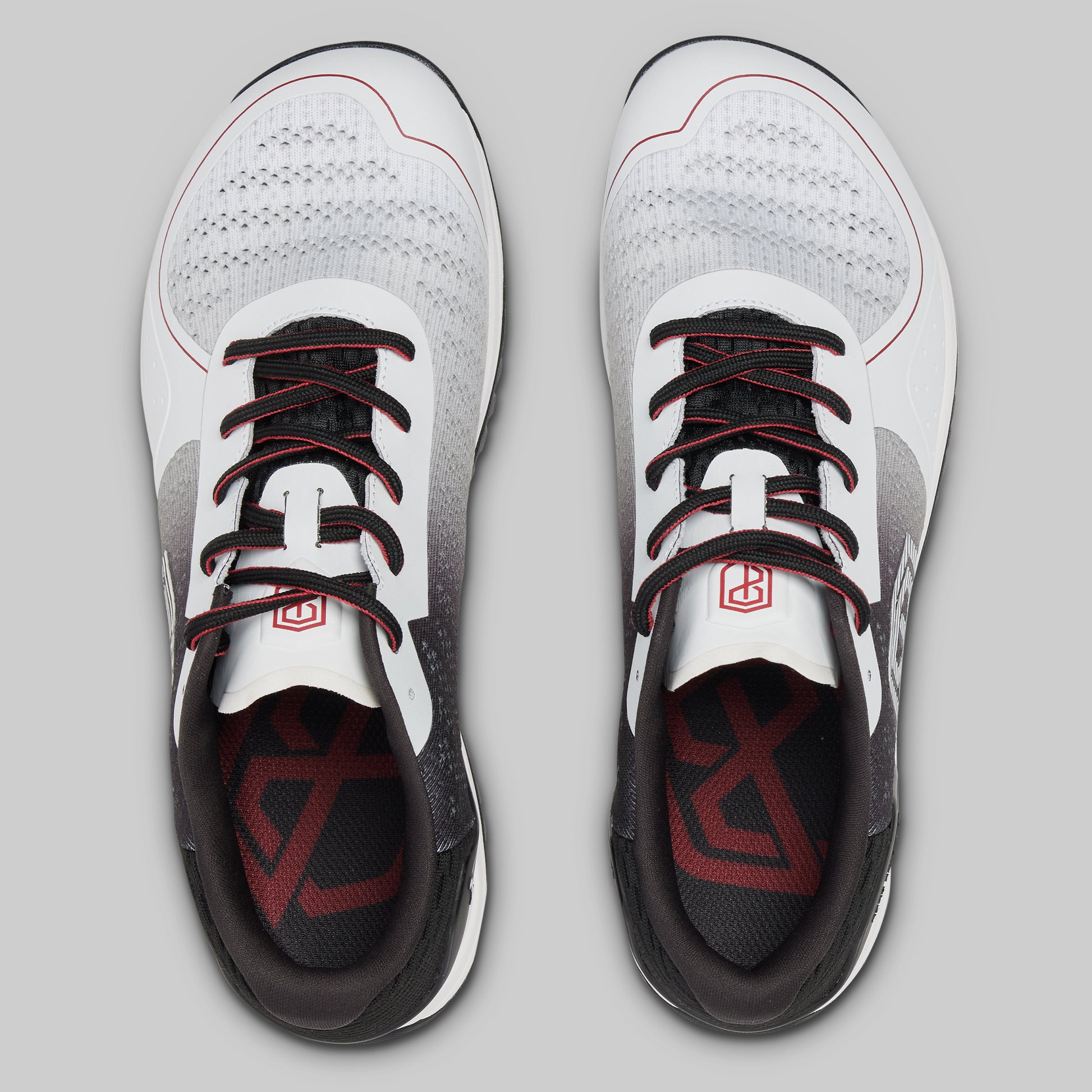 White athletic shoes with black and red accents on a gray background