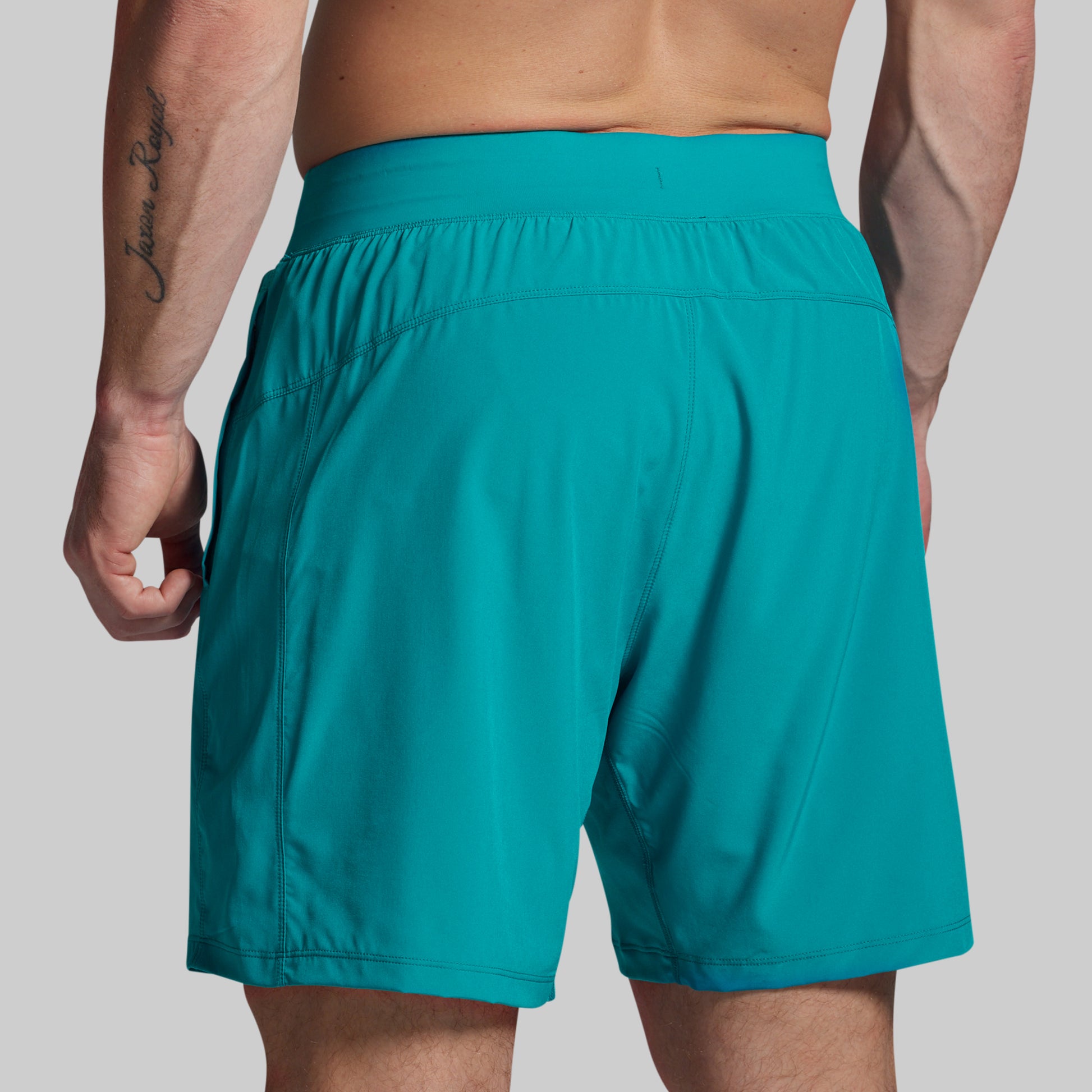 Teal shorts worn by a person on a plain background