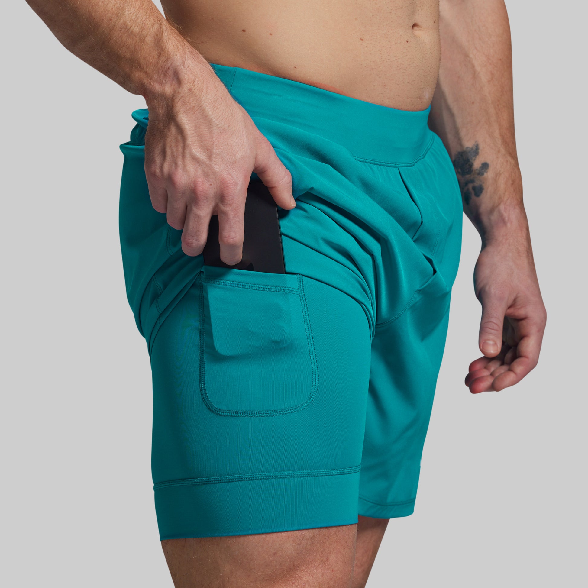 Teal shorts worn by a person on a plain background