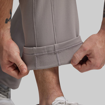 Person wearing gray pants with a close-up of the ankle on a light background