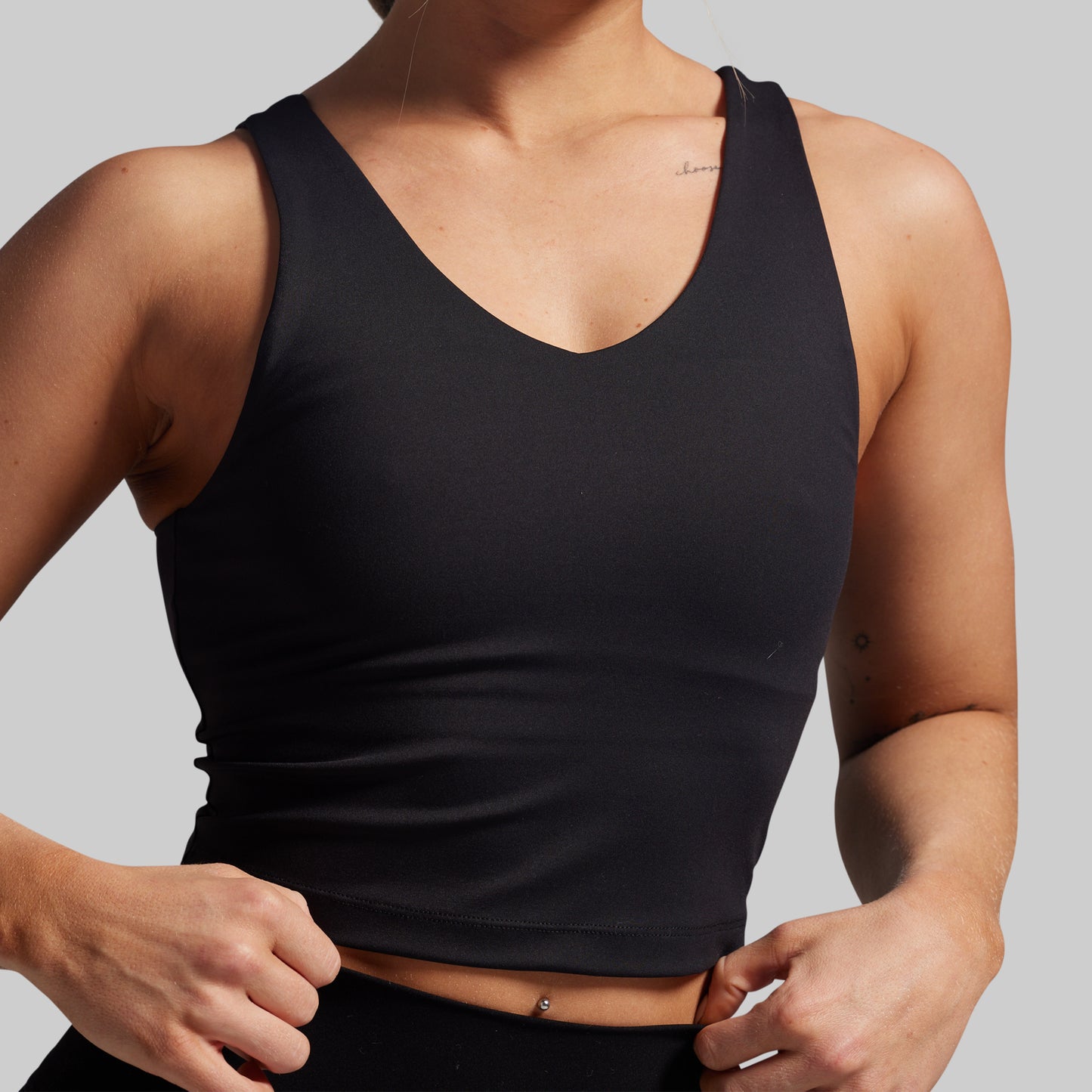 Person wearing a black tank top against a gray background