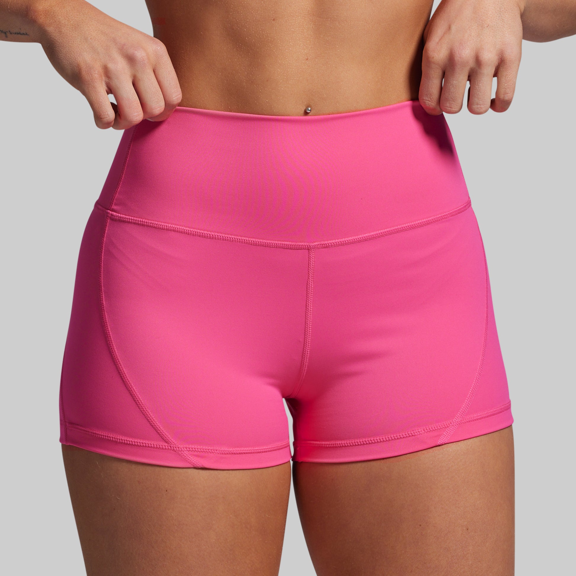 Person wearing bright pink athletic shorts on a gray background