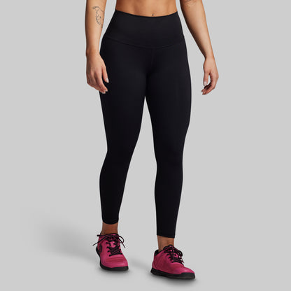 Person wearing black leggings and pink sneakers on a gray background