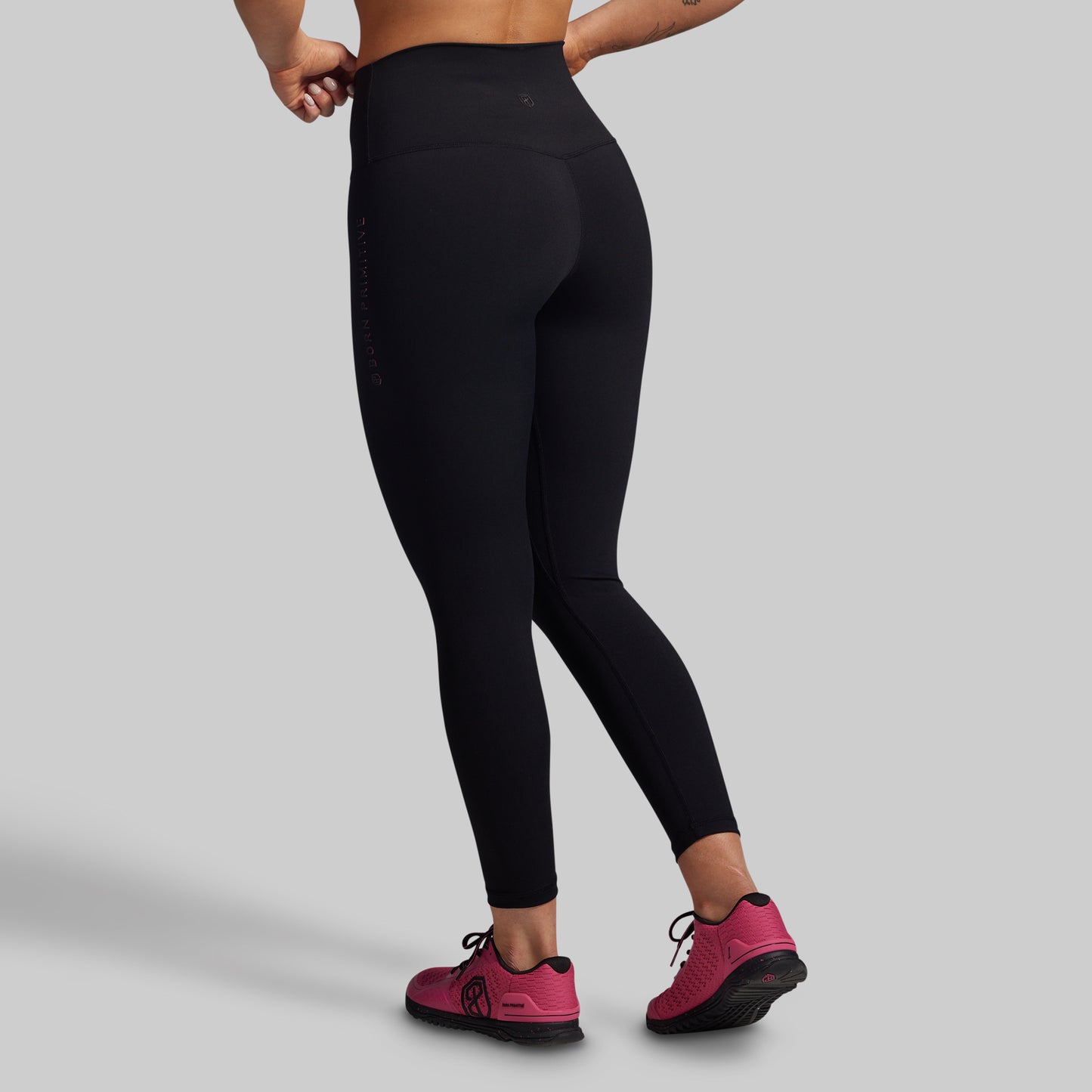 Person wearing black leggings and pink shoes on a gray background