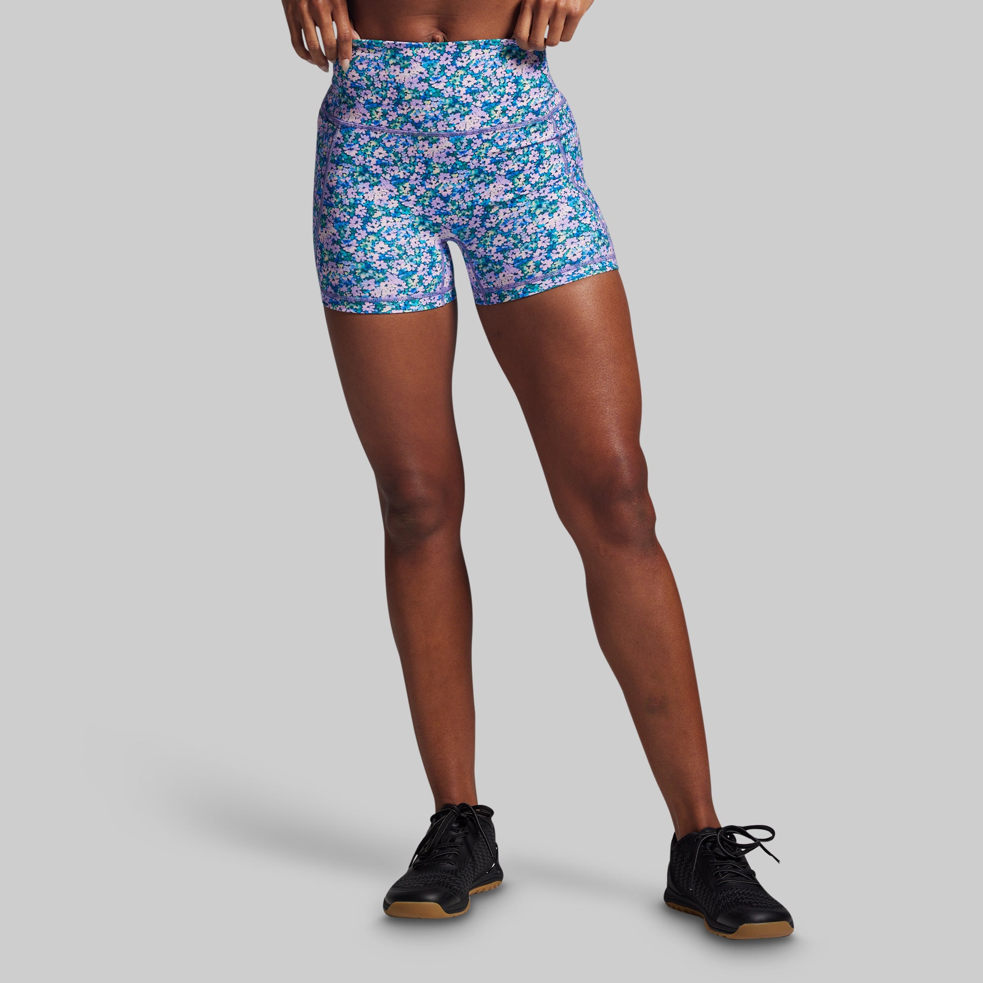 Person wearing colorful floral shorts on a gray background