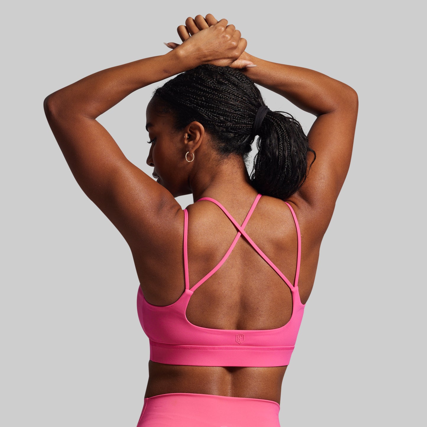 Person wearing a pink sports bra and leggings on a gray background