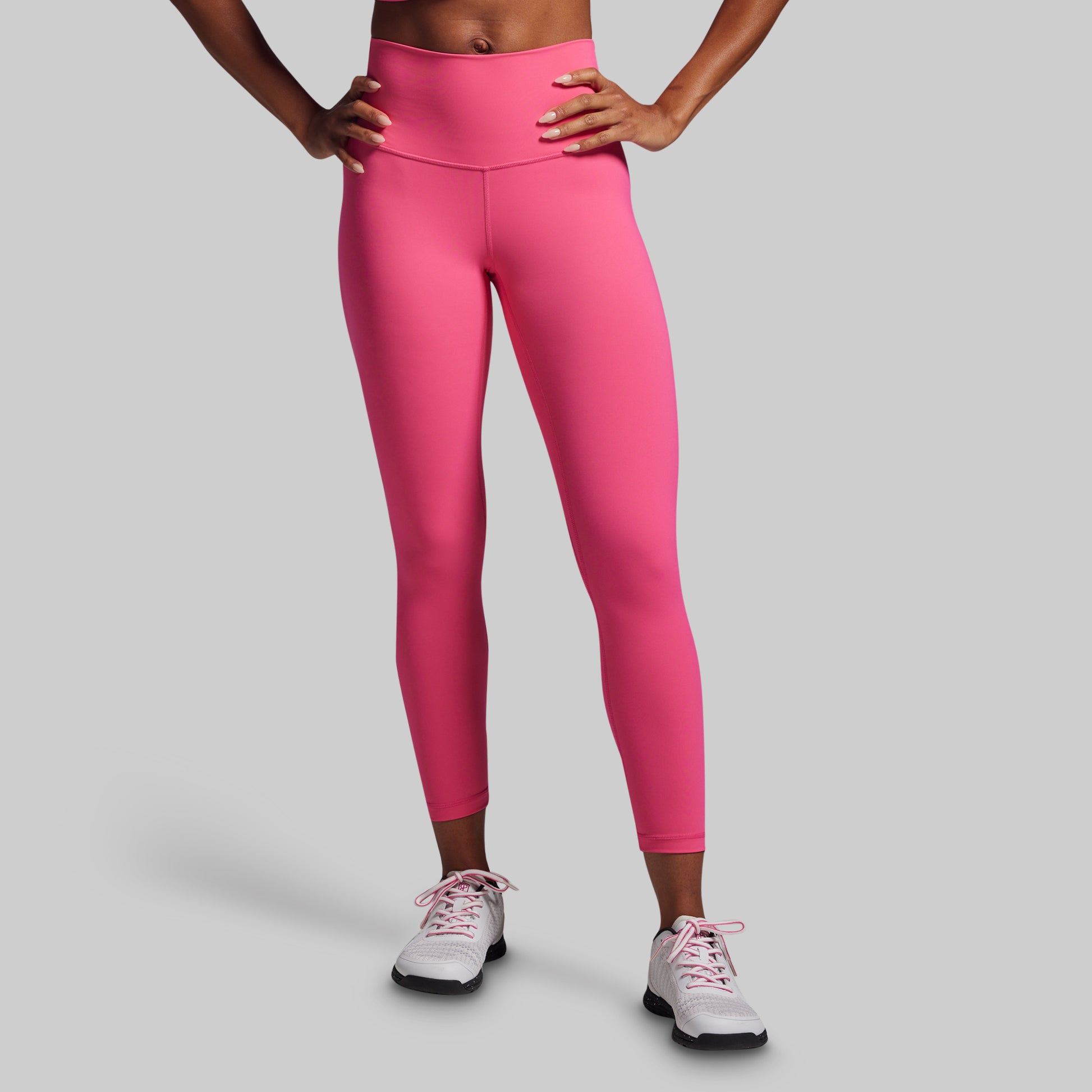Person wearing bright pink leggings on a gray background