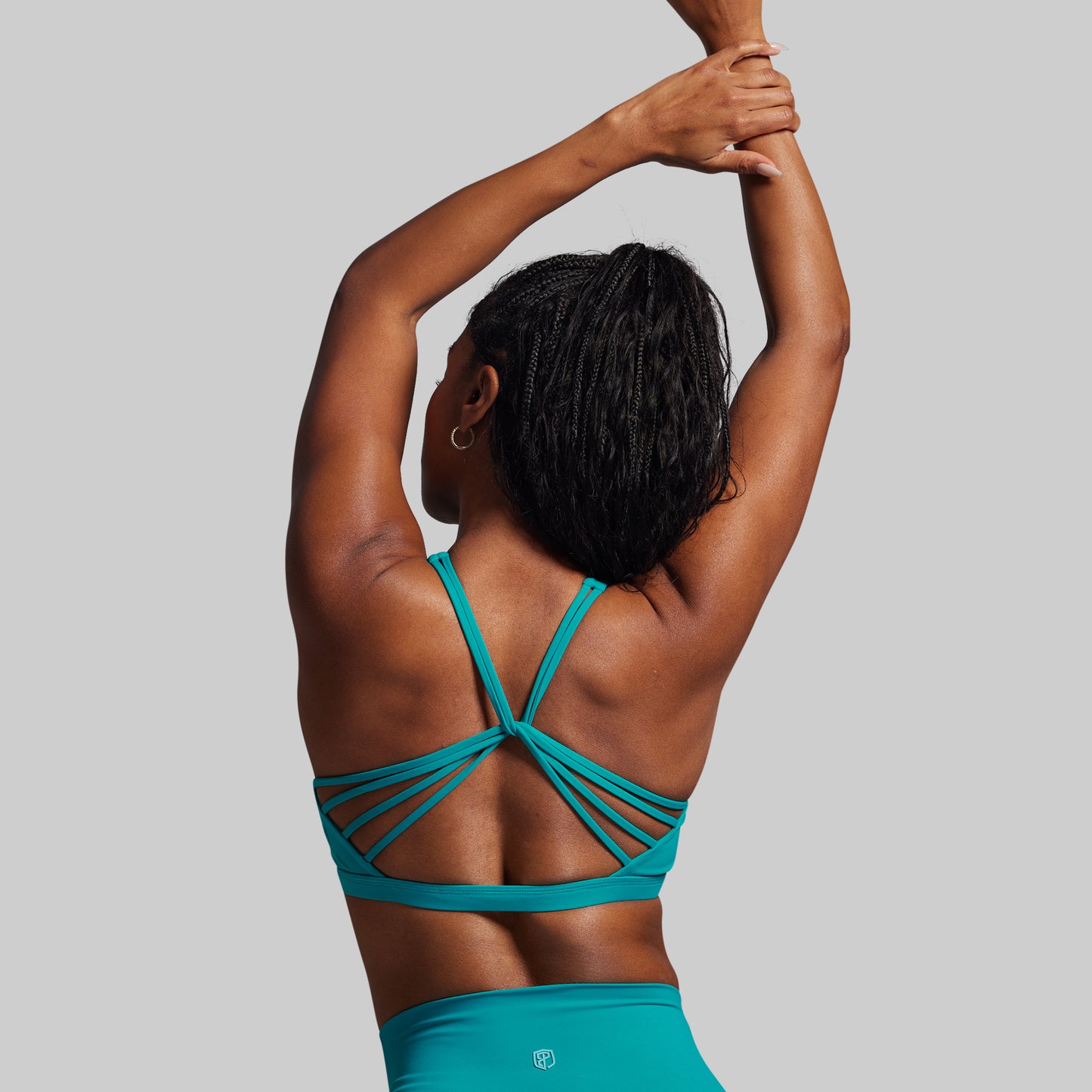 Person wearing a teal sports bra and leggings on a gray background