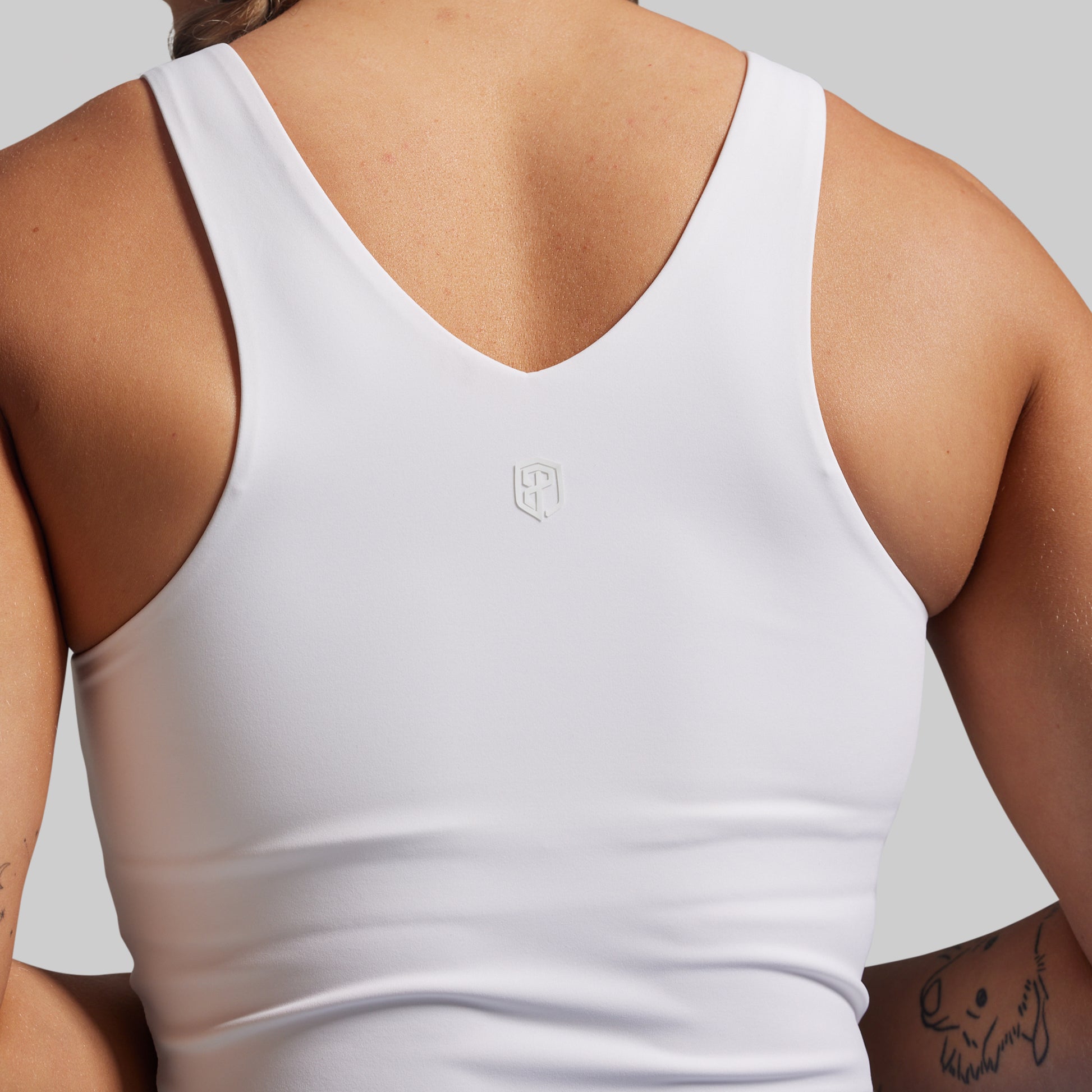 White tank top with a brand logo on a neutral background