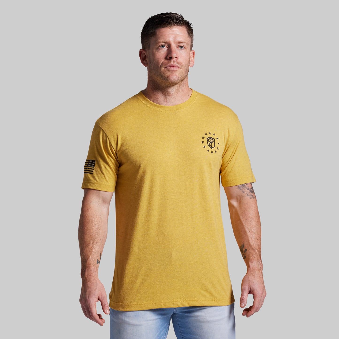 Man wearing a yellow t-shirt with a logo on a gray background
