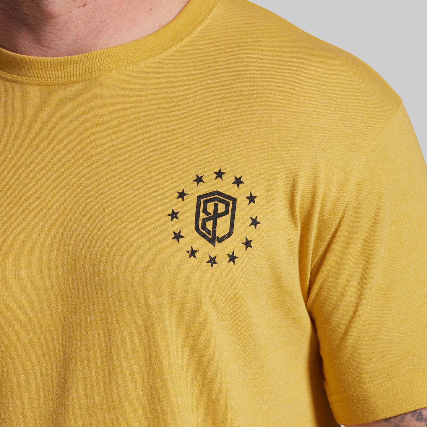 Yellow t-shirt with a black logo and stars on a gray background